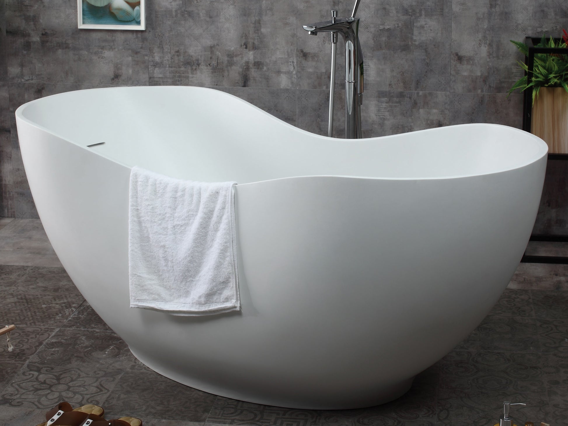 ALFI Brand angled view of a White freestanding bathtub with a towel draped over it in a bathroom setting. - Luxe Tub Source