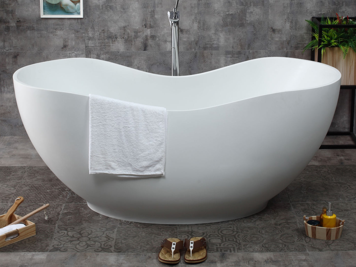 ALFI Brand White freestanding bathtub in a bathroom with a towel draped over it and sandles on the floor. - Luxe Tub Source