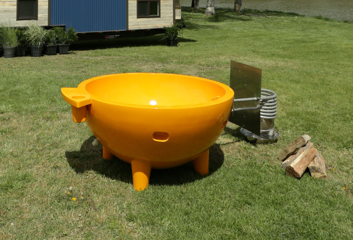 ALFI Brand Yellow Outdoor Wood-Burning Hot Tub on grass with a small building in the background - Luxe Tub Source