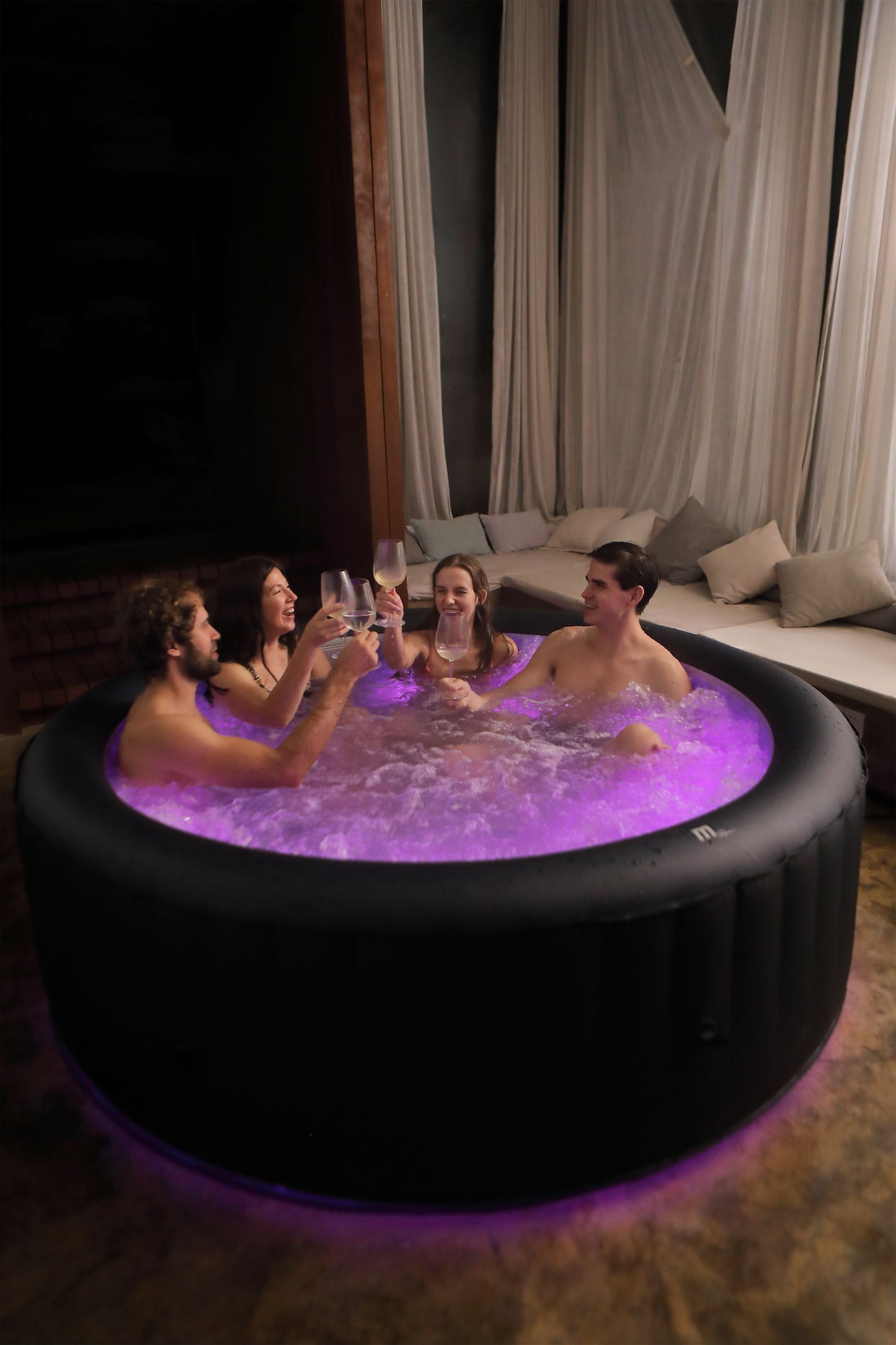 People in a hot tub with purple lighting in a dimly lit room.