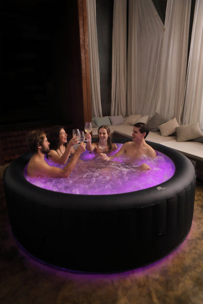 People in a hot tub with purple lighting in a dimly lit room.