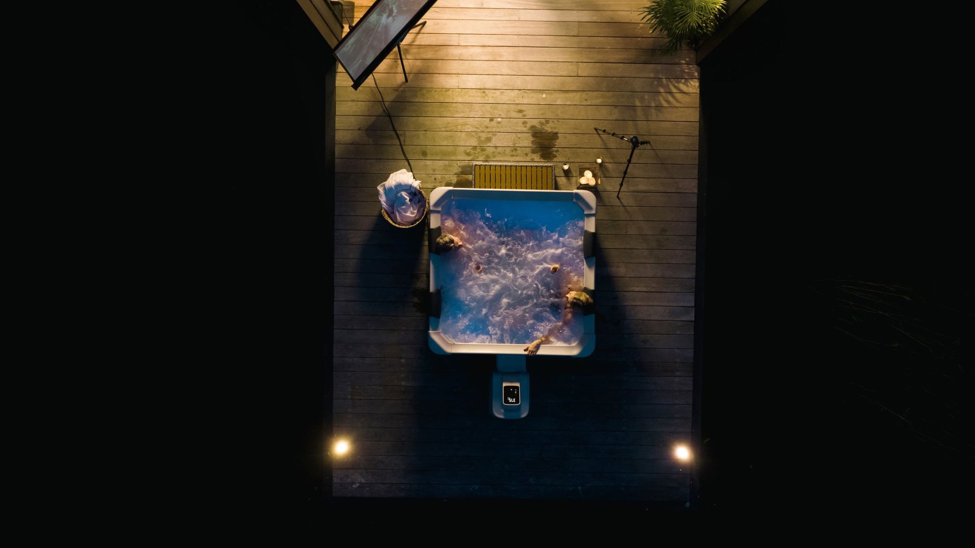 Top-down view of a hot tub on a wooden deck at night.