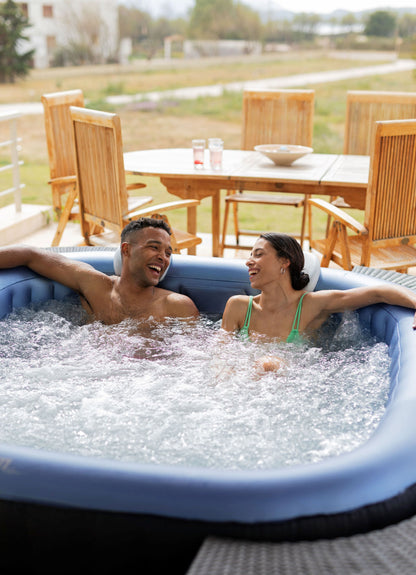 MSpa Two people in a hot tub smiling with a patio and outdoor furniture in the background.  - Luxe Tub Source