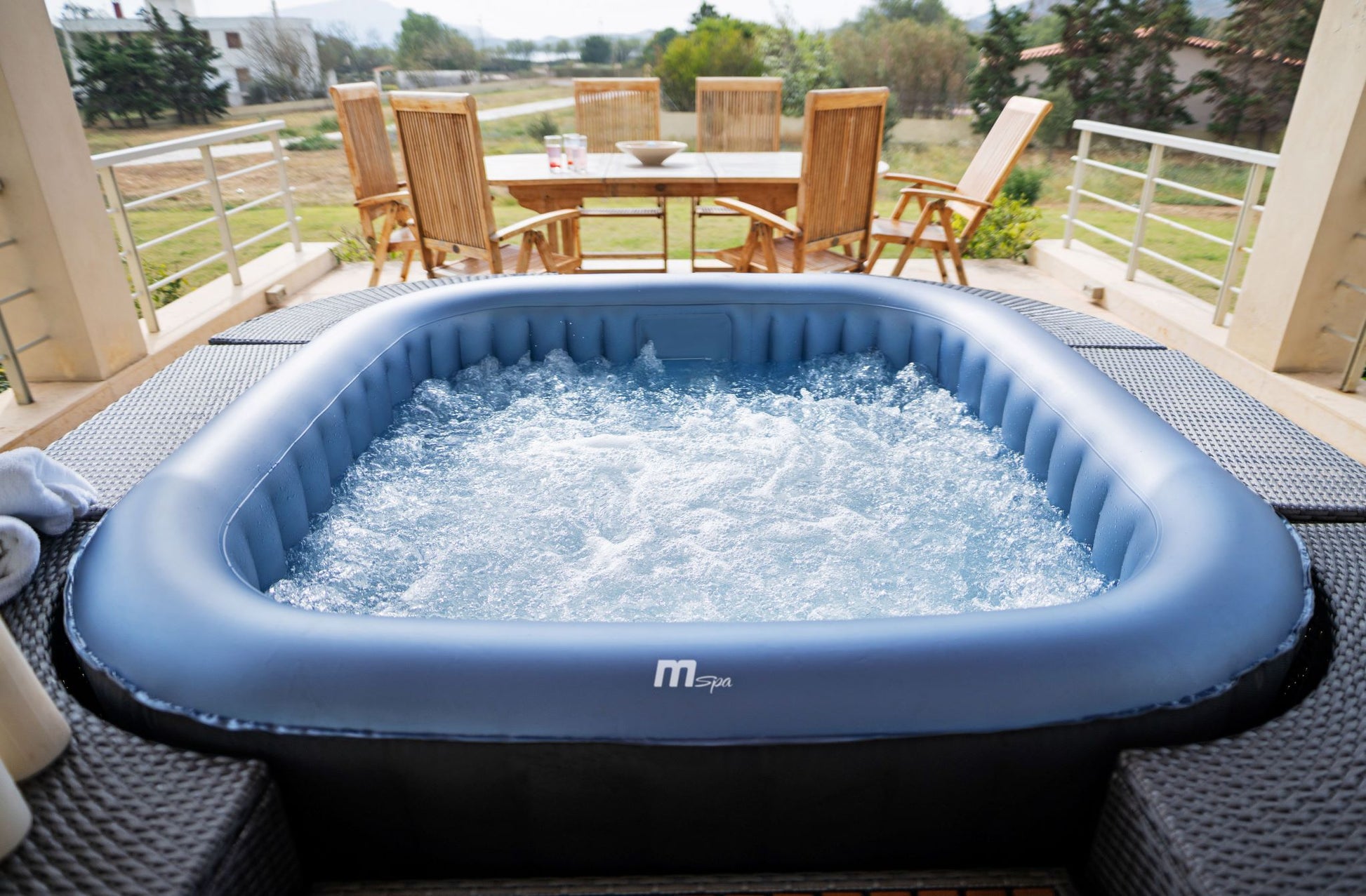 MSpa Inflatable hot tub on a patio with outdoor furniture in the background. - Luxe Tub Source