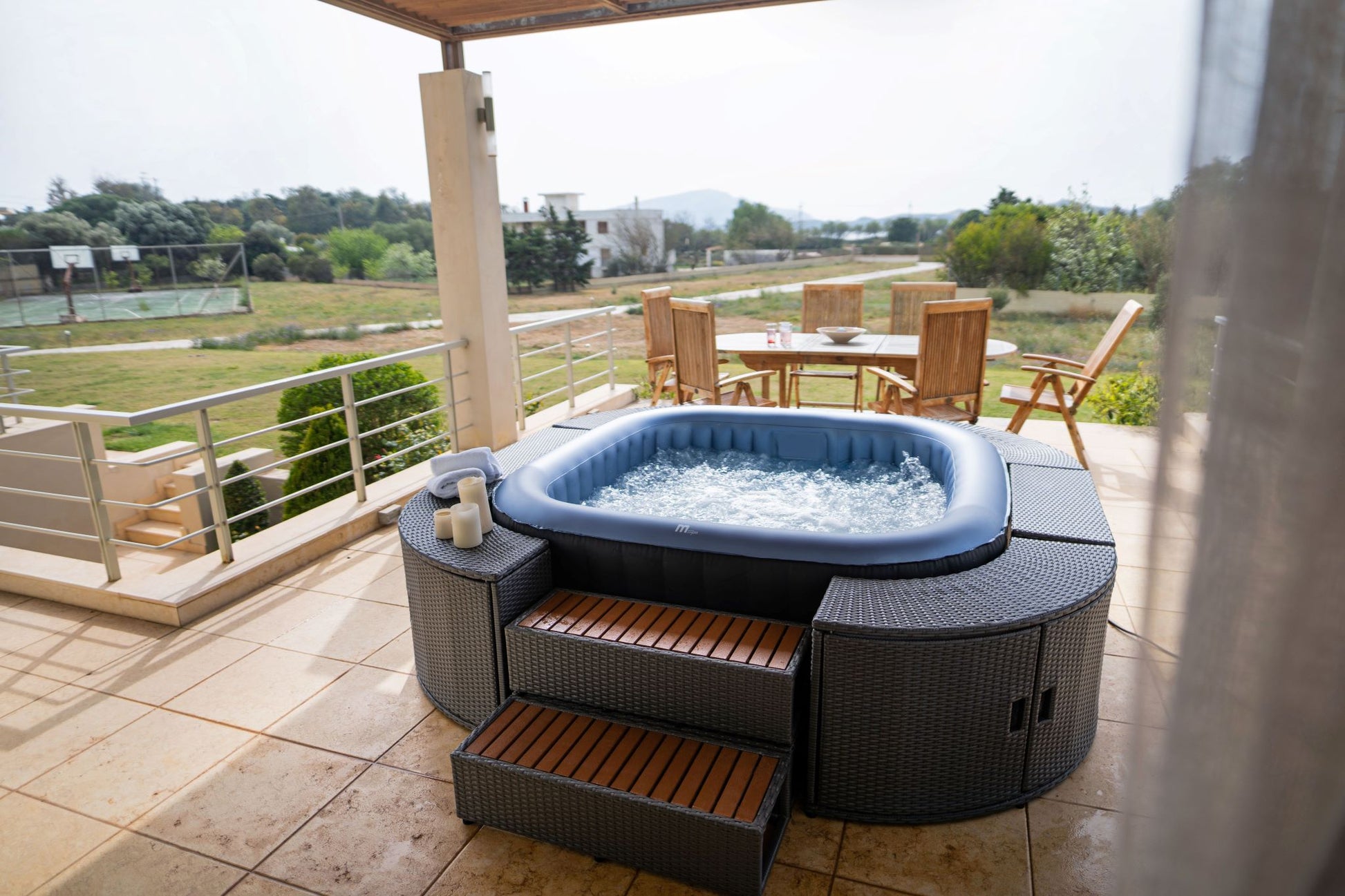 MSpa Hot tub on a patio with outdoor furniture and scenic view.  - Luxe Tub Source