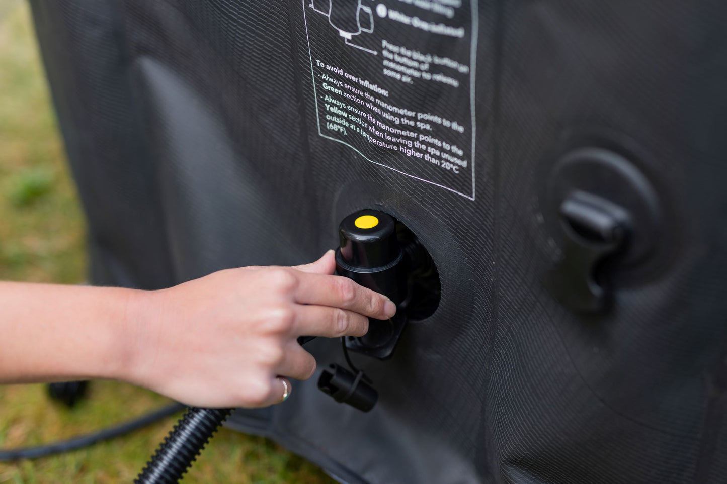 MSpa Person inflating a black inflatable hot tub with a hose and valve.  - Luxe Tub Source