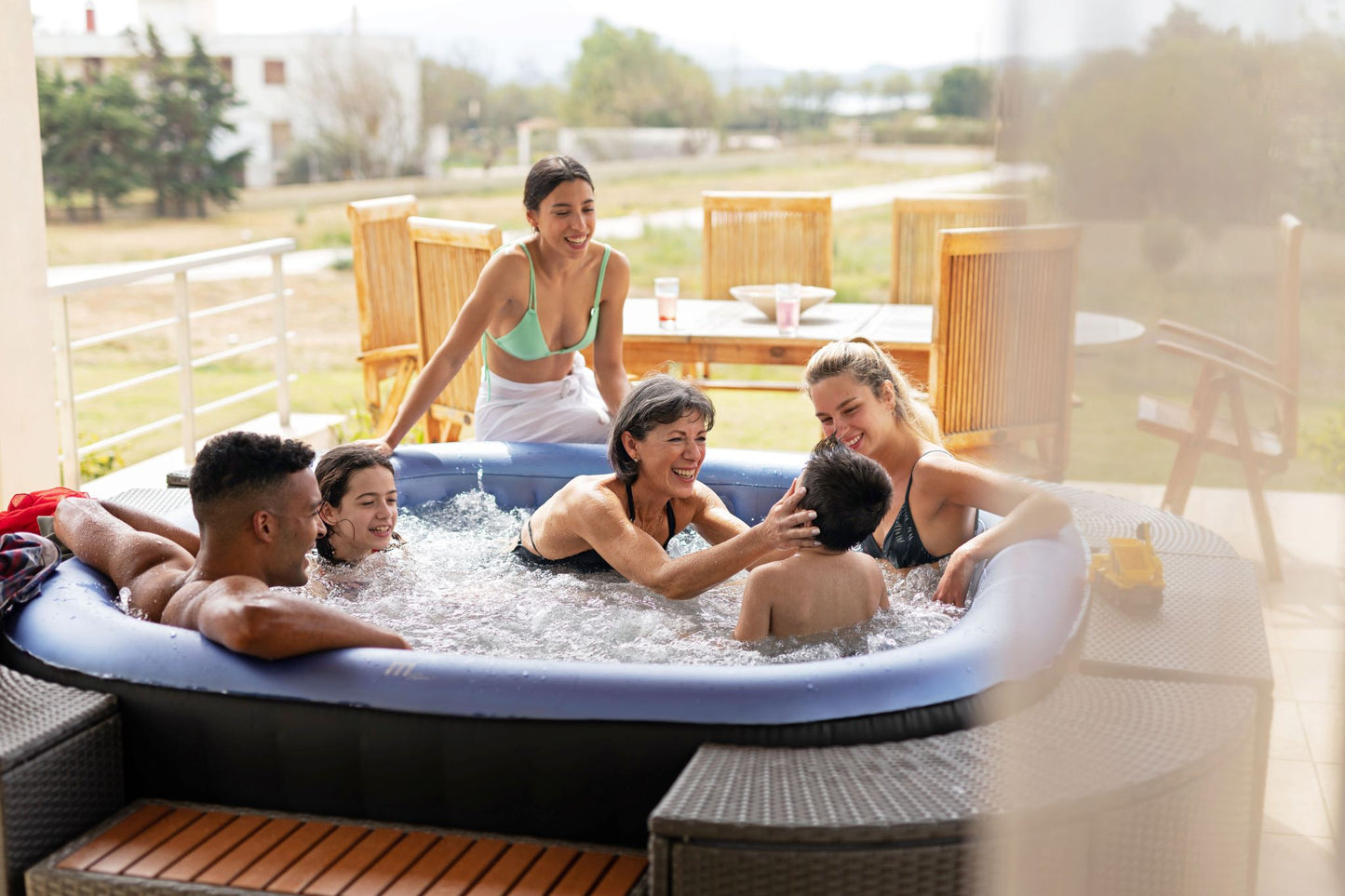 MSpa Group of people enjoying a hot tub on a patio with a scenic background.  - Luxe Tub Source