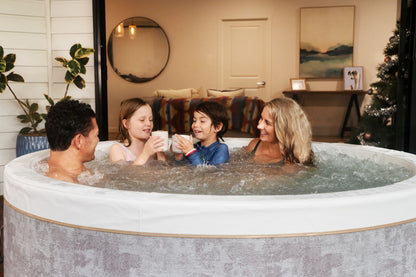 MSpa Family of four in a hot tub in a cozy living room setting. - Luxe Tub Source