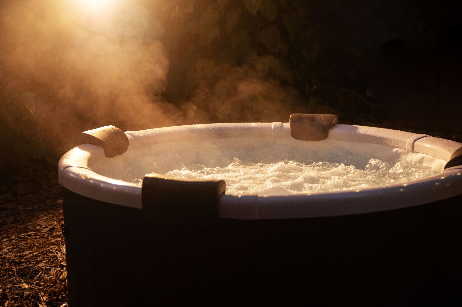 Hot tub with steam rising in a dark outdoor setting