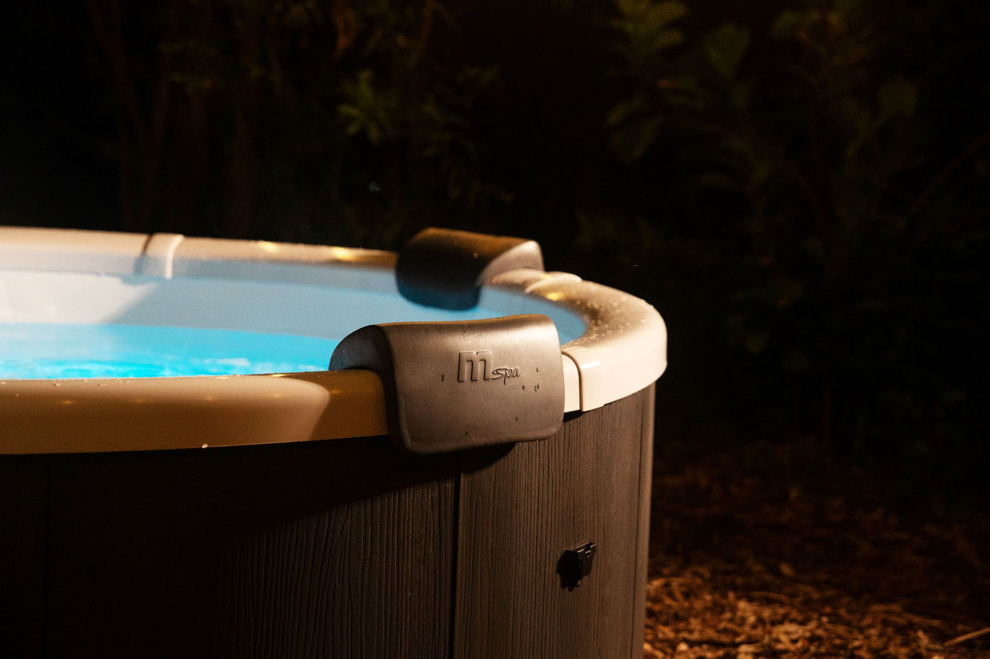 Hot tub with blue water and 'Mspa' branding in a dark outdoor setting