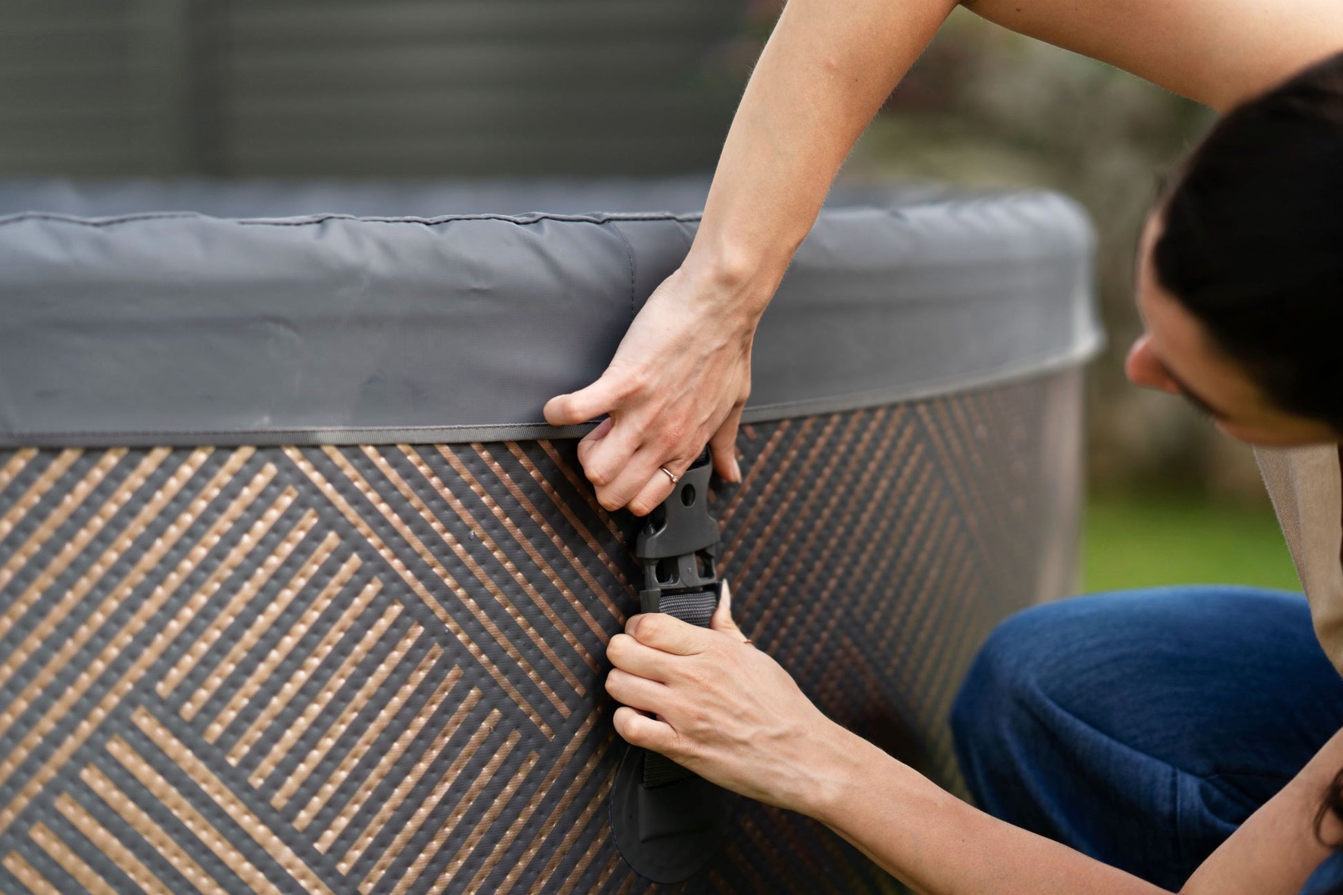 MSpa Person securing a cover on a large outdoor hot tub with a patterned exterior. - Luxe Tub Source