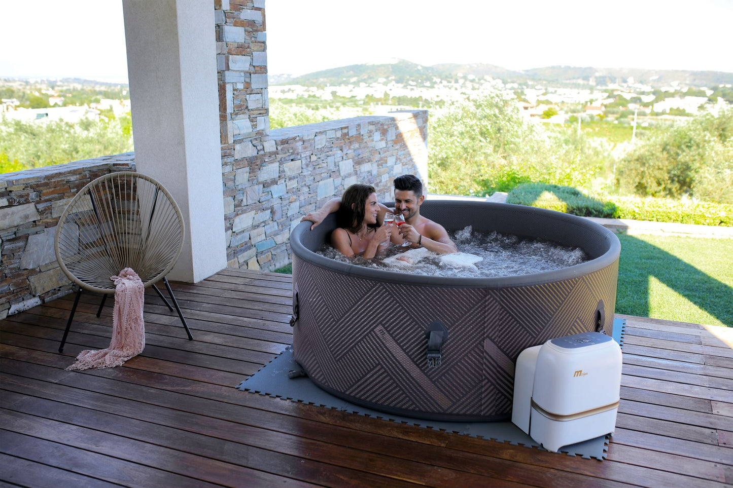MSpa Two people in a hot tub on a wooden deck toasting drinks. - Luxe Tub Source