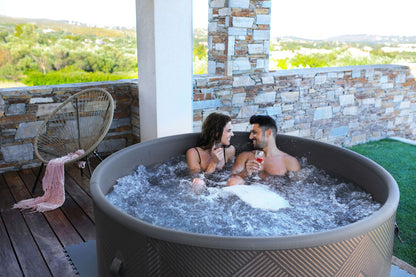 MSpa Couple in a hot tub on a patio with a scenic view. - Luxe Tub Source