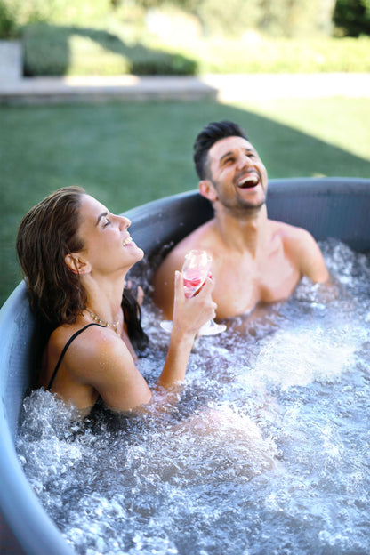 MSpa Couple laughing and enjoying a hot tub together in a garden setting. - Luxe Tub Source