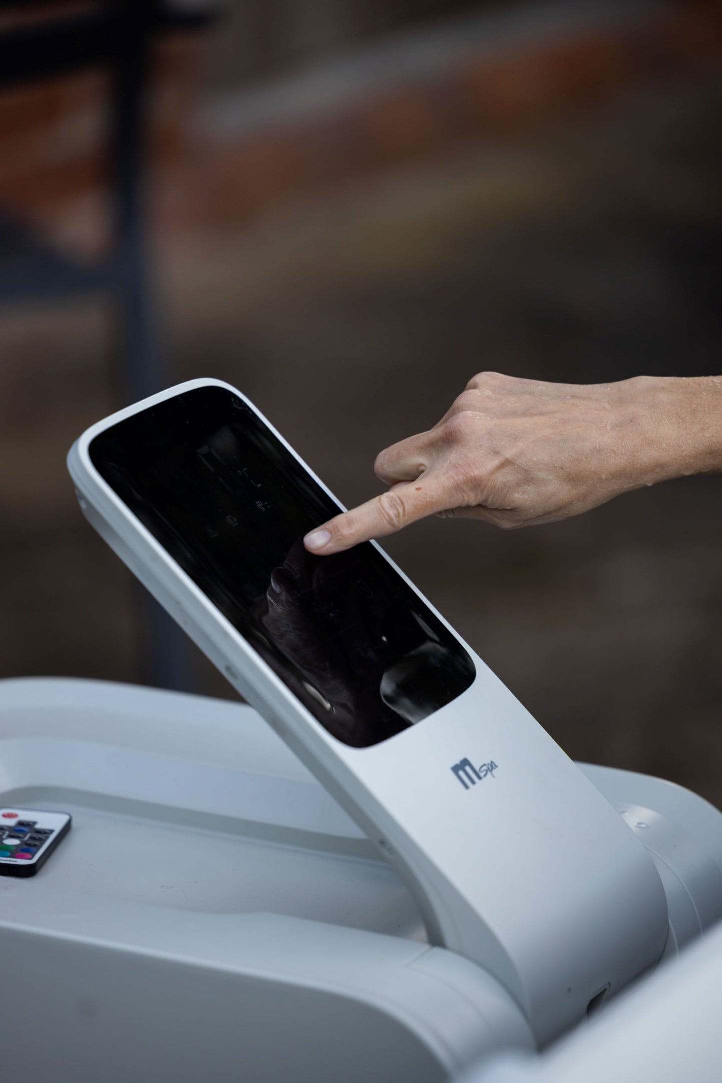 Hand interacting with a touch screen control panel on a hot tub.